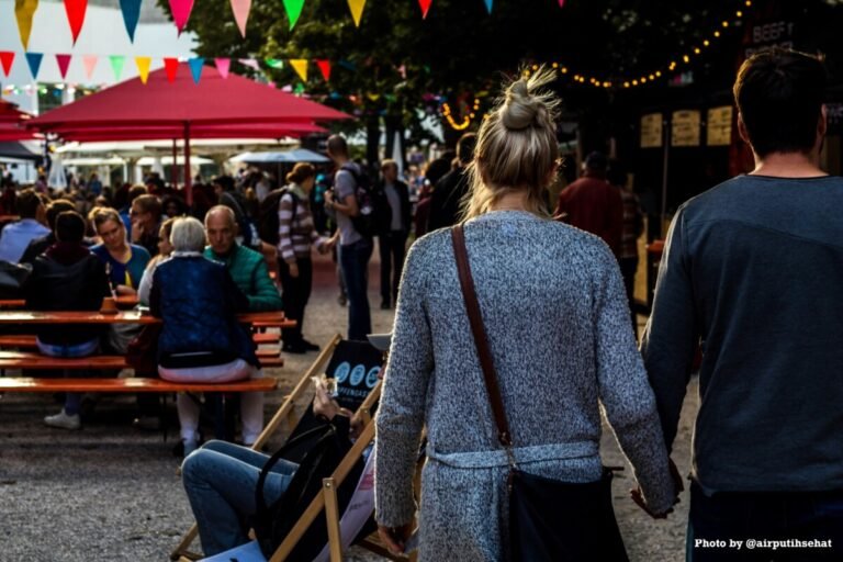 couple holding hands at an event. tent and bunting flags hang