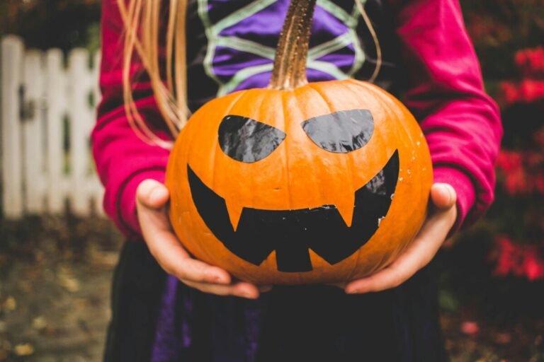 Child holding a carved Halloween pumpkin outdoors